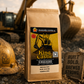 Coffee bag labeled 'King of the Castle' in front of a construction excavator.